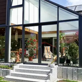 Moderner Wintergarten mit großen Glasfronten und gemütlicher Sitzecke im Gartenhaus.