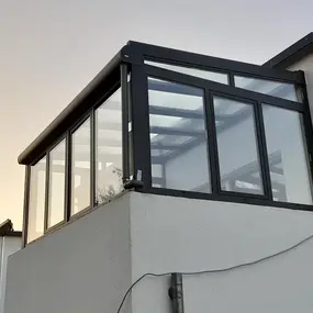 Moderner Wintergarten aus Glas und Aluminium auf Flachdach eines Einfamilienhauses.